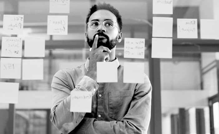 A person looking at a glass wall with sticky notes