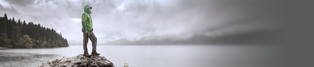 A man standing on a rock with a lake in the background