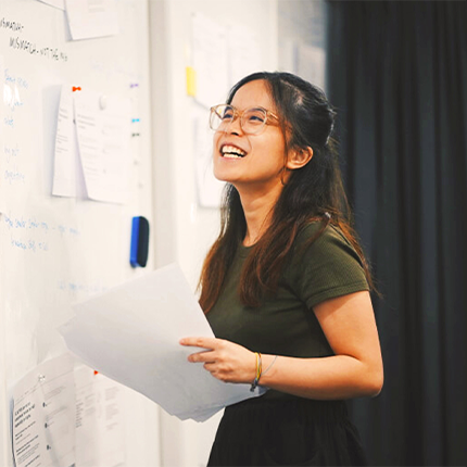 A woman smiling while holding papers