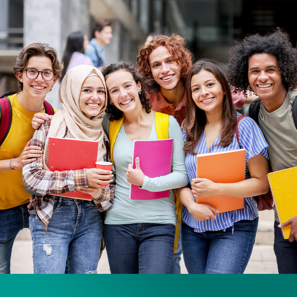Un groupe d’étudiants et étudiantes qui ont des livres et qui sourient à la caméra.