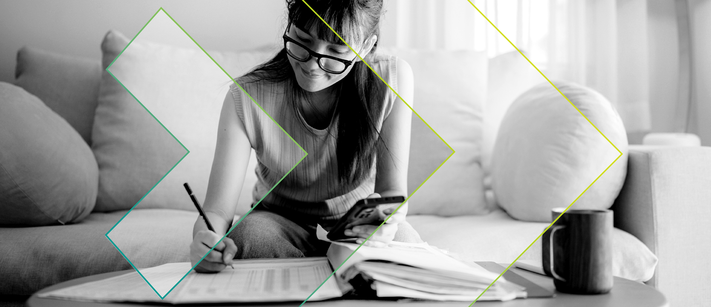 Une femme qui écrit dans un cahier avec un téléphone cellulaire à la main.