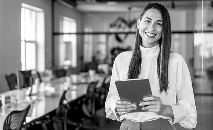 Une femme souriante qui tient un ordinateur portable.