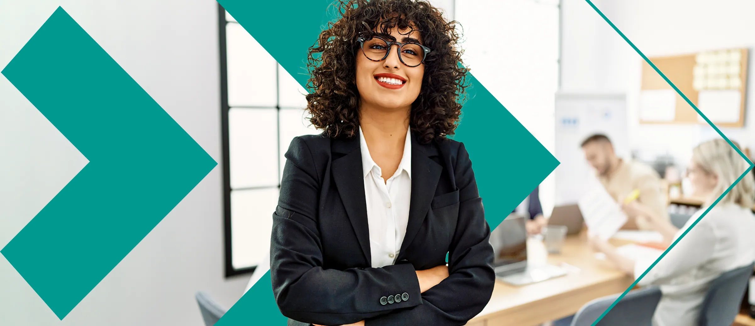 Une femme aux cheveux bouclés qui porte des lunettes et un complet noir.