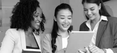 Three women reviewing something on a tablet.