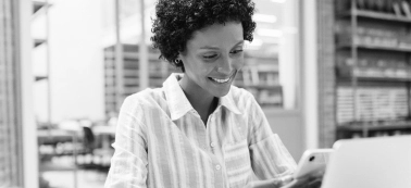 A woman smiling and looking at her phone.
