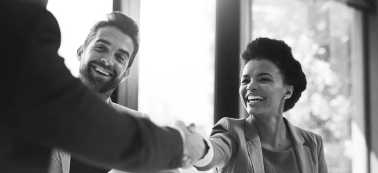 A man and a woman shaking hands and smiling.