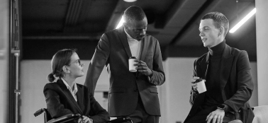 Two men and a woman in an informal office meeting.