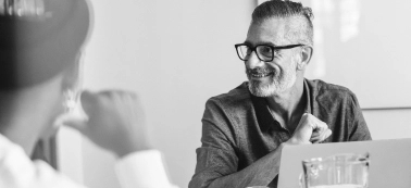 A man smiling in a work meeting.