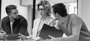 Two men and a woman chatting in a work meeting.