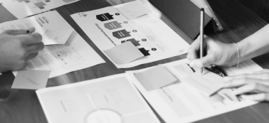 In the frame we see papers on a desk and a hand taking notes.