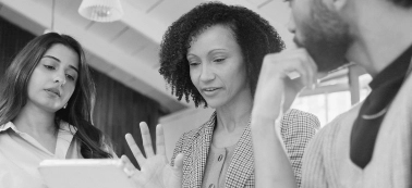 A woman explains something on a tablet to a group of people.