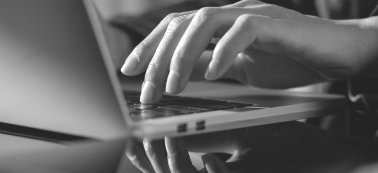A hand and a laptop in the frame.