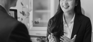 A woman speaks with a man in an office.