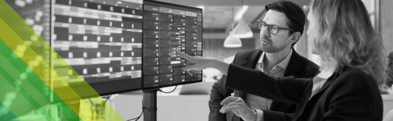 A woman shows something to a man on a screen computer.