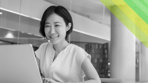 A woman working on a laptop and smiling.