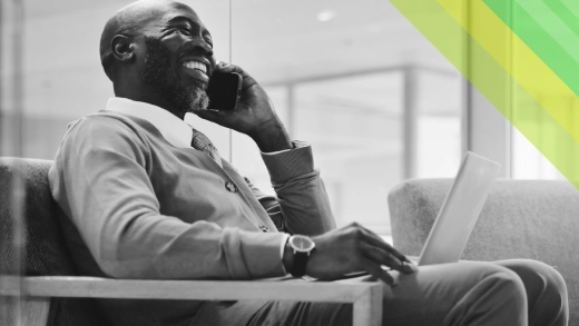 A man speaking on the phone and smiling.